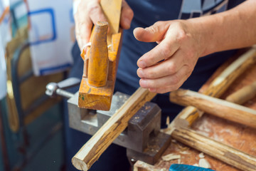 With the help of the plane, there is grinding of the wood in the production of a bird house