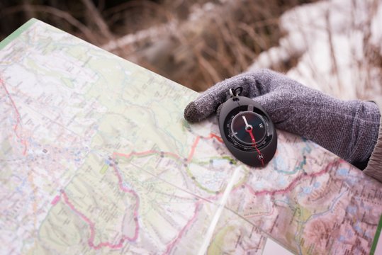 Hand of woman holding compass and map