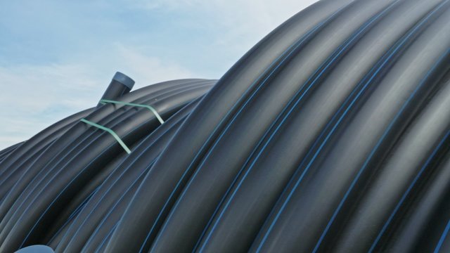 Warehouse of finished plastic pipes industrial outdoors storage site. Manufacture of plastic water pipes factory. Process of making plastic tubes on the machine tool with the use of water and air
