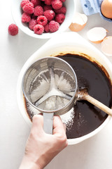 Mixing flour in chocolate brownies batter 