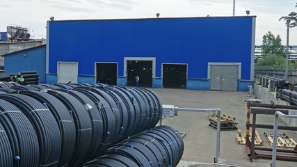 Fototapeta na wymiar Warehouse of finished plastic pipes industrial outdoors storage site. Manufacture of plastic water pipes factory. Process of making plastic tubes on the machine tool with the use of water and air