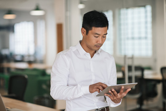 Focused Asian businessman using a tablet in an office
