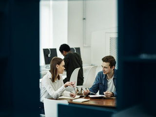 Young cheerful couple talking in library
