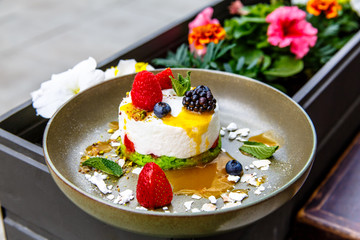 Dessert cheesecake with berries (blackberries, raspberries, strawberries, blueberries) lies on a plate.