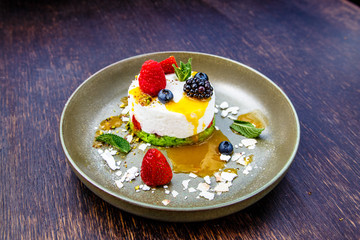 Dessert cheesecake with berries (blackberries, raspberries, strawberries, blueberries) lies on a plate.