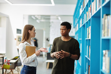 Multiethnic couple discussing studying in library