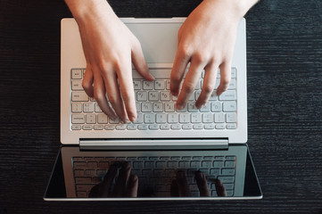 Top view of human hands typing on laptop keyboard isolated on black