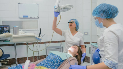 Woman at dentist clinic gets dental treatment to fill a cavity in a tooth. Dental restoration and...