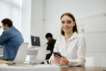 Charming student holding smartphone