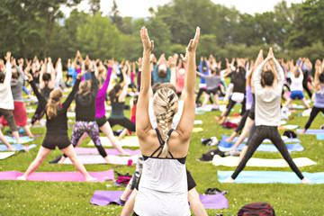 big group of adults attending a yoga class outside in park