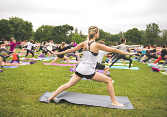 big group of adults attending a yoga class outside in park