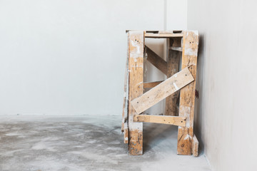 Old construction wooden ladder on on the background a white plastered wall