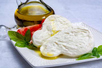 Fresh soft Italian white cheese mozzarella buffalo, original from Campania, Paestrum and Foggia regions, South Italy, served with tomatoes, fresh basil and olive oil