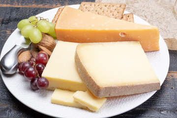 Aged English cheddar and old Dutch cheese, the most popular type of hard cheeses made from cow milk served as a dessert with nuts and grapes