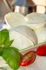 Fresh soft Italian white cheese mozzarella buffalo, original from Campania, Paestrum and Foggia regions, South Italy, served with tomatoes and fresh basil