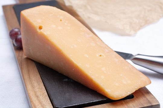 Piece of hard matured 3 years old dark yellow cheese close up