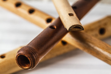 Simple wooden flutes on a background of pure sheet music © Nbaturo