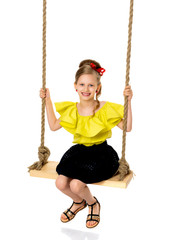 Joyful little girl swinging on a swing.