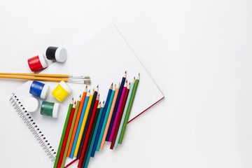 Fototapeta premium Drawing notebook, gouache paints, colored glue, colored glitter and colored pencils on the white surface
