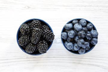 Full bowls of berries over white wooden surface, top view. Summer berry. From above, overhead, flat lay.