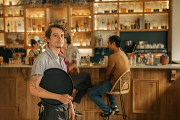 Waiter standing in a trendy bar ready to serve customers