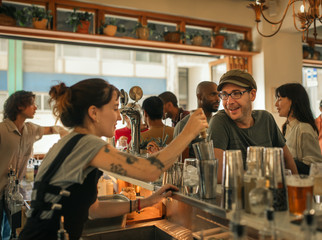 Smiling patron ordering drinks in a trendy bar - obrazy, fototapety, plakaty