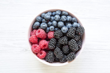Pink bowl of fresh berries: blackberry, raspberry, blueberry, top view. Summer berry. From above, overhead. Closeup.