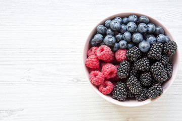Full pink bowl of fresh berries, view from above. Summer berry. Top view, overhead. Copy space.