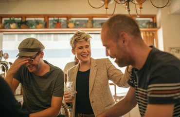 Friends laughing and having drinks together in a bar