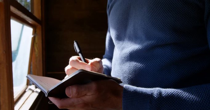 Man writing on a diary at home 4k