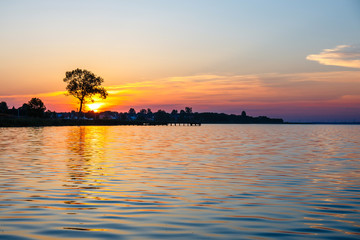 Fototapeta na wymiar Sunrise over the lake with the tree in the background