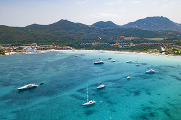 Obraz premium Aerial view of some yachts and sailing vessel on a turquoise and transparent sea. Emerald Coast, Mediterranean sea, Sardinia, Italy.
