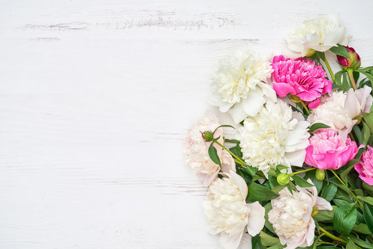 White and pink peonies flowers on white wooden background. Holiday background, copy space, top view.