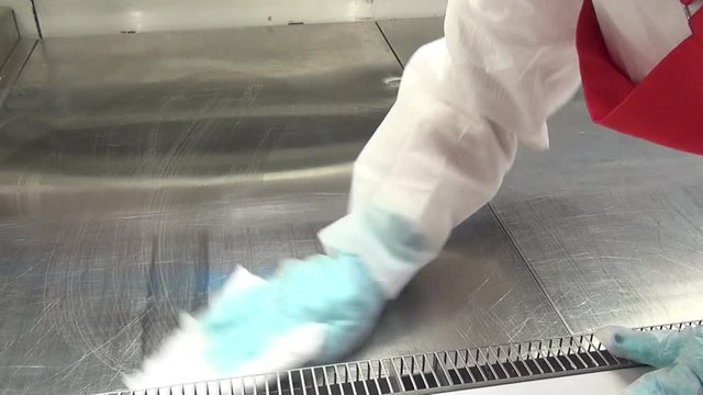 Hand of worker cleans the refrigerator in a supermarket. Sanitary treatment of industrial equipment. Chemical detergents.