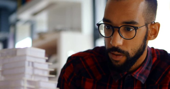 Male architect looking at building model 4k
