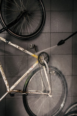Services professional washing of bicycle in the workshop. Close-up of hand Young Caucasian stylish man doing bicycle cleaning using an automatic electric water pump. Sprays scatter from the pressure.