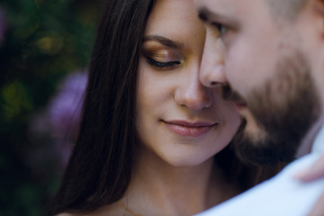 Close up romantic couple of man and woman hugging outdoors in the garden near the purple flower bush. Wedding concept
