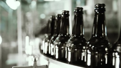 Automatic filling machine pouring beer in a brewery. Glass bottles for beer on the conveyor belt. Filling machine for industry.
