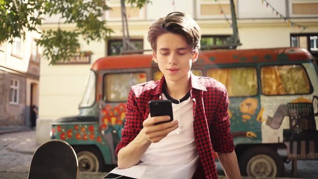 Smiling boy using a mobile phone sitting keeps skate smile guy business fashion hand child man nature internet social smartphone face boy lifestyle smart teenager young cell modern communication