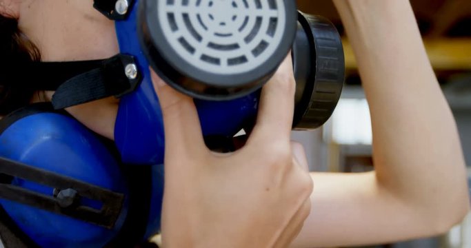 Female welder wearing gas mask in workshop 4k