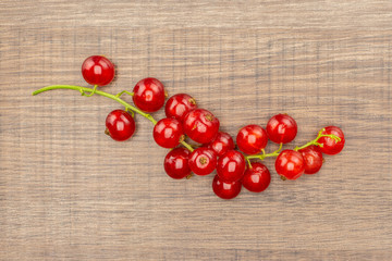 One whole red currant berry string flatlay isolated on brown wood.