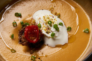 Lentil cream soup with baked lamb, cream fresh and spearmint. Delicious healthy soup food in bowl plate on table background, close-up, top view
