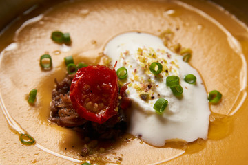 Lentil cream soup with baked lamb, cream fresh and spearmint. Delicious healthy soup food in bowl plate on table background, close-up, top view