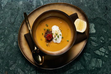 Lentil cream soup with baked lamb, cream fresh and spearmint. Delicious healthy soup food in bowl plate on table background, close-up, top view