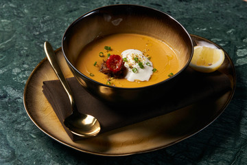 Hot Lentil cream soup with baked lamb, cream fresh and spearmint. Delicious healthy soup food in bowl plate on table background, close-up, top view