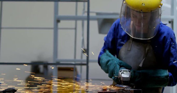 Female welder using grinder in workshop 4k