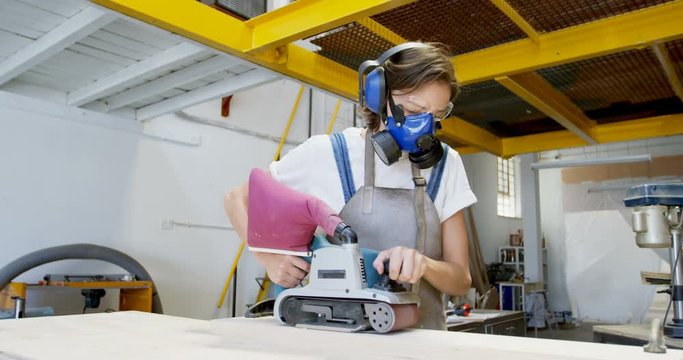 Female welder using wood sanding machine 4k