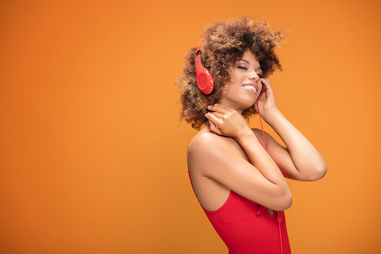Adorable happy afro girl with red headphones .
