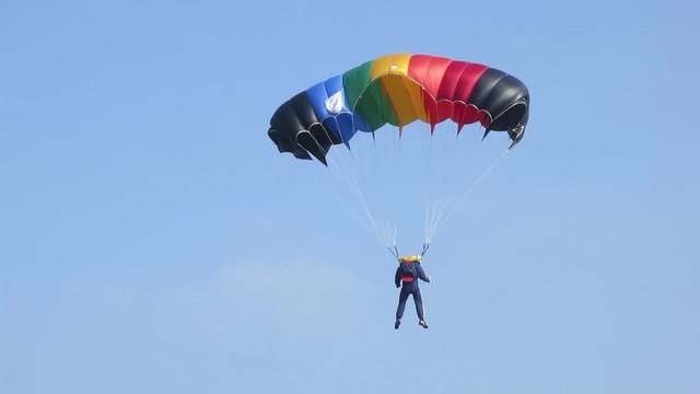 Person landing with a rainbow colored parachute.