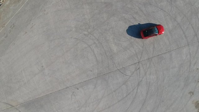 Droneshot of red car (ferrari) doing doughnuts